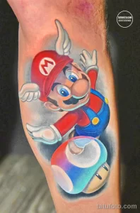 Фото тату Марио из Super Mario Bros на предплечье. Цветная татуировка с изображением героя, прыгающего над трубой.