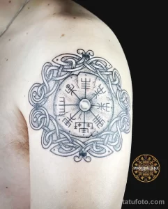 Фото тату кельтского компаса (Vegvísir) на плече. Черно-белый рисунок татуировки с руническими символами и кельтскими узорами.