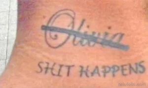 Фото тату: татуировка имени "Olivia" и фразы "Shit Happens" на коже, выполненная простым шрифтом.