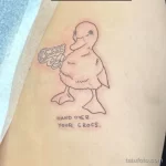 Фото тату: утка с пистолетом и надписью "HAND OVER YOUR CROCS", выполненная в черном цвете. Расположение - предплечье.