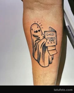 Фото тату на руке: милое привидение держит книгу с надписью 'Ghost Stories Rated XXX', выполненное в черно-белой технике с использованием точек и штрихов.