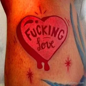 Фото тату красного сердца с надписью "Fucking Love". Простой, но выразительный рисунок татуировки с использованием яркого цвета.
