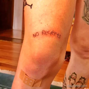 Фото татуировки с надписью 'No Regrets', выполненной простым шрифтом на руке.