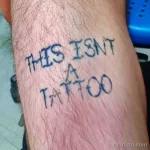 Фото тату с надписью 'THIS ISN'T A TATTOO' на руке. Ироничный рисунок татуировки, пример самоиронии и юмора.