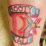 Фото тату на руке: бутылочка с надписью 'Booty Call', украшенная сердечком и пистолетом, выполненная в ярких цветах.