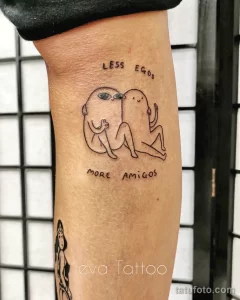 Фото тату: два человечка, обнимающие друг друга, надпись "Less Ego, More Amigos", минималистичный стиль, черные линии.