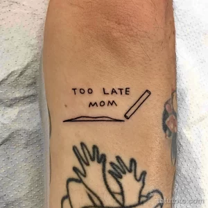 Необычное фото тату с надписью 'Too Late Mom' и изображением сигареты в руке, выполненное в стиле sketch.