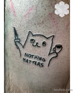 Фото тату: минималистичное изображение кота с ножом в лапе и надписью 'NOTHING MATTERS' на руке.