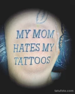 Фото тату с надписью "MY MOM HATES MY TATTOOS", выполненное черным цветом на коже, демонстрирует бунтарский дух и юмор.