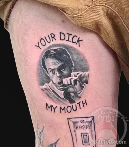 Фото татуировки на бедре с реалистичным портретом мужчины и надписью 'YOUR DICK MY MOUTH', выполненной в черно-белой гамме.