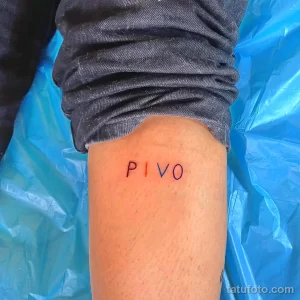 Фото тату с надписью 'PIVO' черным цветом, выполненной простым шрифтом на внутренней стороне голени. Минималистичный рисунок татуировки.