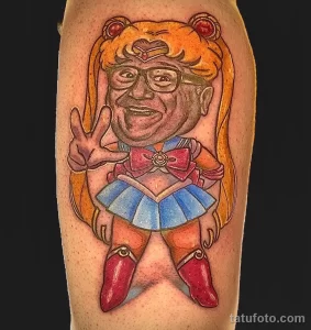 Фото тату: яркая и гротескная татуировка Sailor Moon с лицом Дональда Трампа, выполненная в мультяшном стиле.