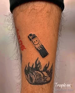 Фото тату: изображение зажигалки и пламени, выполненное в реалистичном стиле с использованием черных и серых оттенков.