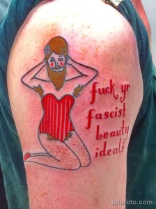 Фото татуировки женщины с бородой в купальнике и надписью "fuck yr fascist beauty ideals". Яркий и смелый эскиз татуировки.