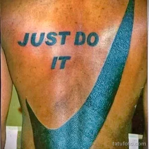Фотография татуировки с надписью "Just Do It" и логотипом Nike на спине. Татуировка, вдохновленная известным слоганом спортивного бренда.