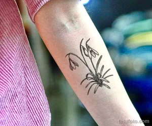 Фото тату эскиза подснежников на руке. Черно-белый рисунок, тонкие линии, минималистичный стиль. Идеи для тату.