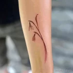 Фото минималистичной татуировки подснежника на руке. Тонкие линии, лаконичный дизайн, акцент на форме и изяществе цветка. Эскиз тату в стиле line art.