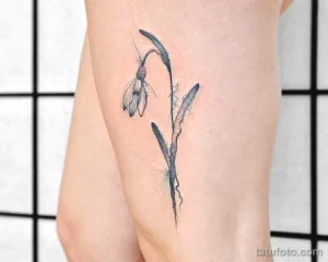 Фото татуировки подснежника на бедре, выполненной в технике dotwork. Использование точек создает эффект объема и детализации.