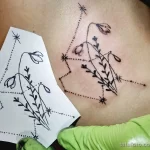Фото тату: татуировка подснежников на груди, выполненная в минималистичном стиле с использованием точек и звезд. Эскиз татуировки дополнен тонкими линиями и узорами.