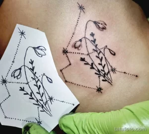 Фото тату: татуировка подснежников на груди, выполненная в минималистичном стиле с использованием точек и звезд. Эскиз татуировки дополнен тонкими линиями и узорами.