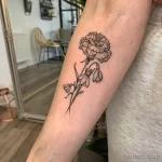 Фото татуировки с изображением подснежника и пиона на руке, выполненной в технике blackwork. Детализированный рисунок и контрастные тени.