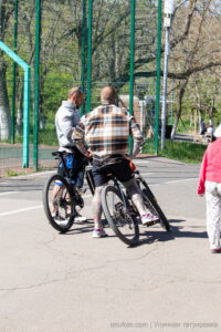 Фото тату на ногах мужчины, катающегося на велосипеде. Яркие, цветные рисунки в стиле традиционной татуировки, покрывающие голени и бедра.
