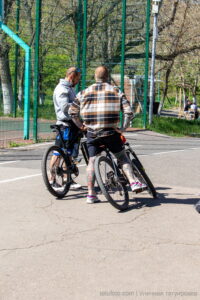 Фото тату на ногах мужчины, катающегося на велосипеде. Яркие, цветные рисунки в стиле традиционной татуировки, покрывающие голени и бедра.