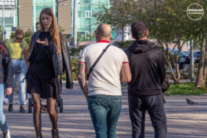Фотография девушки в черной кожаной куртке и мужчина с татуировкой на руке. Городской пейзаж на заднем плане.
