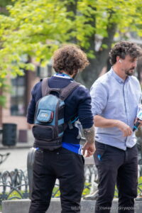 Фото тату на руке мужчины, стоящего на улице. Видна часть татуировки в ярких цветах, выполненной в стиле традишнл.