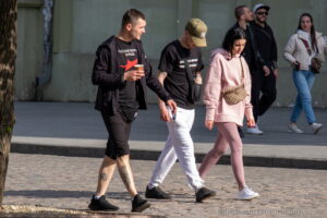 Фотография мужчины с татуировкой на ноге, идущего по улице с друзьями. Видна детализированная татуировка, выполненная в реалистичном стиле.