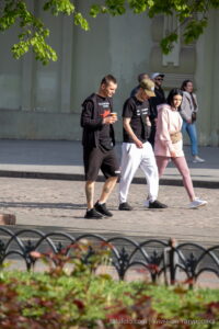 Фотография мужчины с татуировкой на ноге, идущего по улице с друзьями. Видна детализированная татуировка, выполненная в реалистичном стиле.