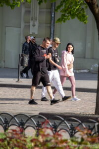 Фото мужчины с татуировкой на ноге, идущего по улице в черной одежде. Детализированный рисунок татуировки с изображением абстрактного узора.