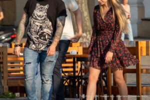 Фото тату на руке мужчины с изображением волка в скафандре космонавта. Рядом с ним идет девушка в красном платье.