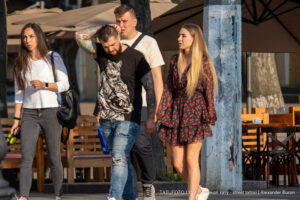 Фото тату на руке мужчины с изображением волка в скафандре космонавта. Рядом с ним идет девушка в красном платье.
