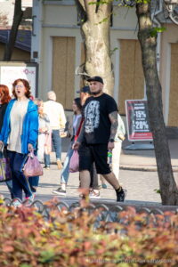 Фото мужчины с татуировкой волка на руке, идущего по улице в кепке. Детализированный рисунок татуировки с реалистичным изображением головы волка.