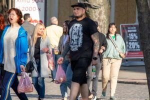 Фото тату волка на руке мужчины, идущего по улице. Детализированный рисунок татуировки с реалистичным изображением головы волка.