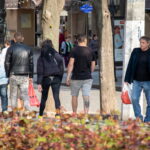 Фото тату волка на голени мужчины, выполненное в геометрическом стиле с использованием черных линий и точек. Виден общий план улицы.