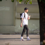 Фото мужчины, идущего по улице с собакой на поводке и видимой татуировкой на руке. Татуировка выполнена в черно-серых тонах.