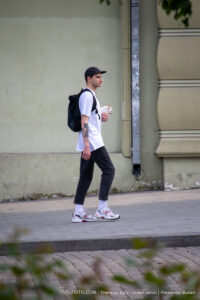 Фото мужчины, идущего по улице с собакой на поводке и видимой татуировкой на руке. Татуировка выполнена в черно-серых тонах.
