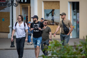 Фотография четырех мужчин, идущих по улице. У двоих видны татуировки на руках, выполненные в разных стилях. Снимок сделан в формате street tattoo.