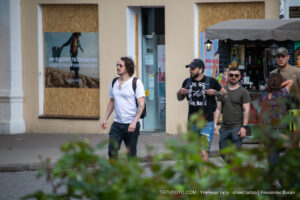 Фотография трех мужчин, идущих по улице. У одного из них видна татуировка льва на руке, у другого - татуировки на руках в стиле графика. Снимок в стиле street tattoo.