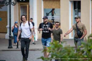 Фотография четырех мужчин, идущих по улице. У одного из них видна татуировка льва на руке, у другого - татуировки на руках в стиле графика. Снимок в стиле street tattoo.