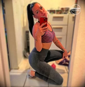 Фотография девушки с небольшой татуировкой в виде бабочки и надписи на руке, выполненной в минималистичном стиле.
