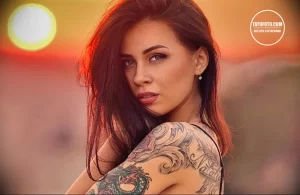 Фотография девушки с длинными волосами и татуировкой дракона на руке. Тату выполнено в ярких цветах и детально проработано.
