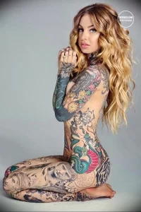 Фотография девушки с полным боди-артом из татуировок. На теле видны рисунки цветов, животных и узоров.