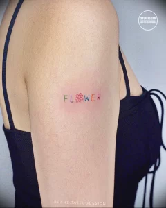 Фото тату надписи 'FLOWER' на руке. Простой и минималистичный дизайн в красном и зеленом цветах. Стильный эскиз тату для девушек.