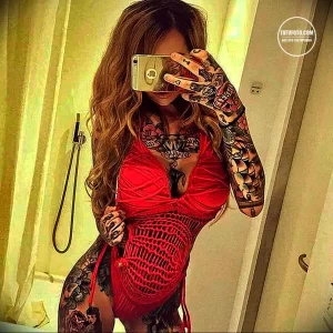 Фотография девушки, делающей селфи с татуировками на руках и теле, демонстрирующими яркие и детализированные рисунки.