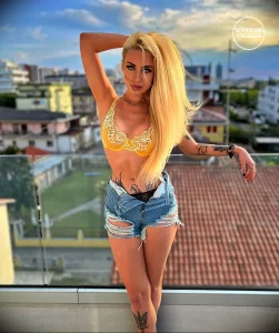 Фотография девушки с яркой татуировкой в виде дракона на руке и талии, демонстрирующая смелый и эффектный дизайн.