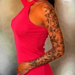Фотография женской руки, полностью покрытой татуировками с изображением цветов и листьев. Подчеркивает красоту и детализацию татуировки в стиле флора.