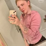 Фотография девушки с татуировкой на руке, изображающей цветок с листьями, выполненной в черно-белом стиле.